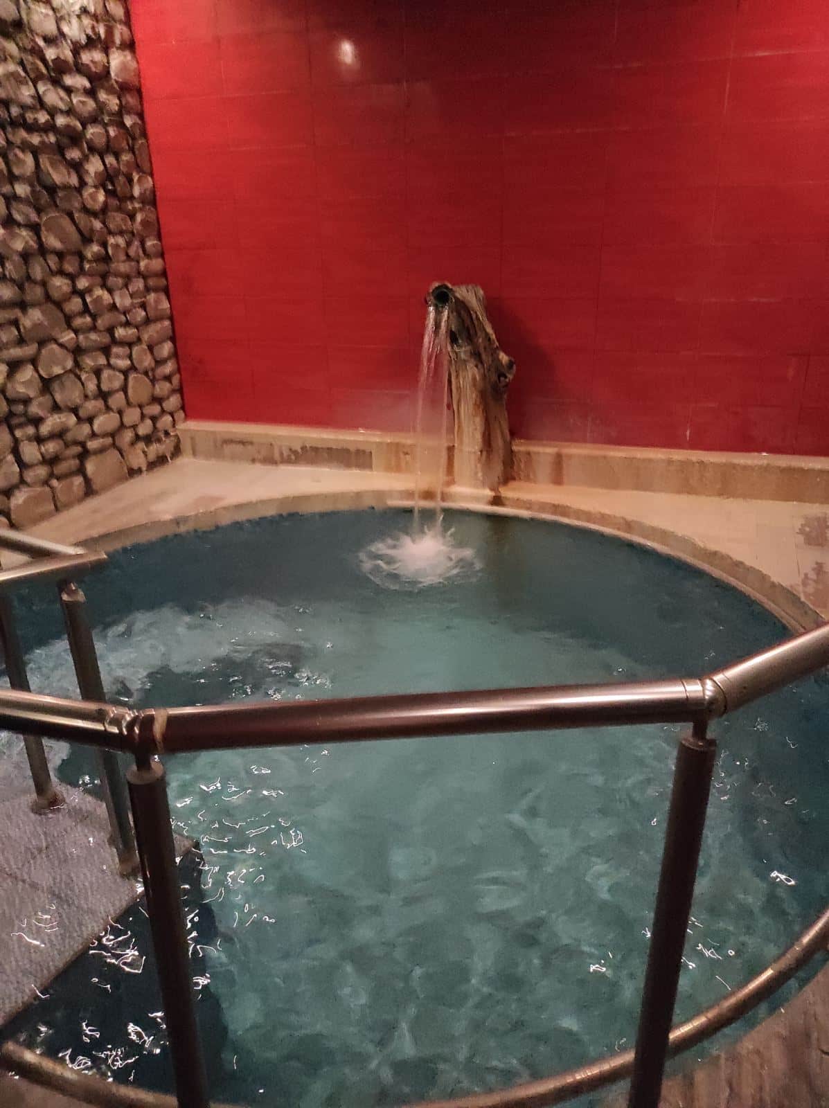 Un bassin privé d'eau thermale aux murs de pierre et de brique rouge, à Loutra Pozar