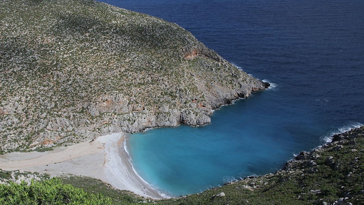 Crique sauvage de sable et de galets au pied d'une colline de maquis à Kalymnos